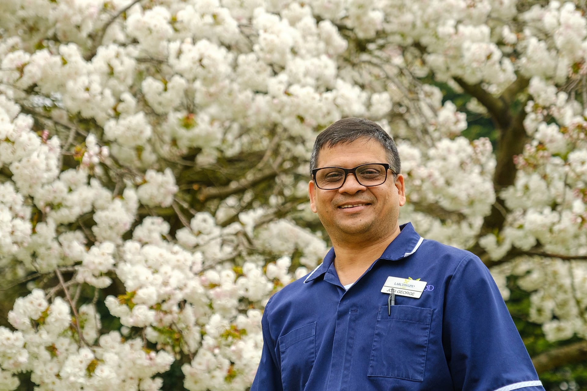 Manager of Mundy House Care Home in Basildon, Josi George in front of a tree in blossom in the home's garden.