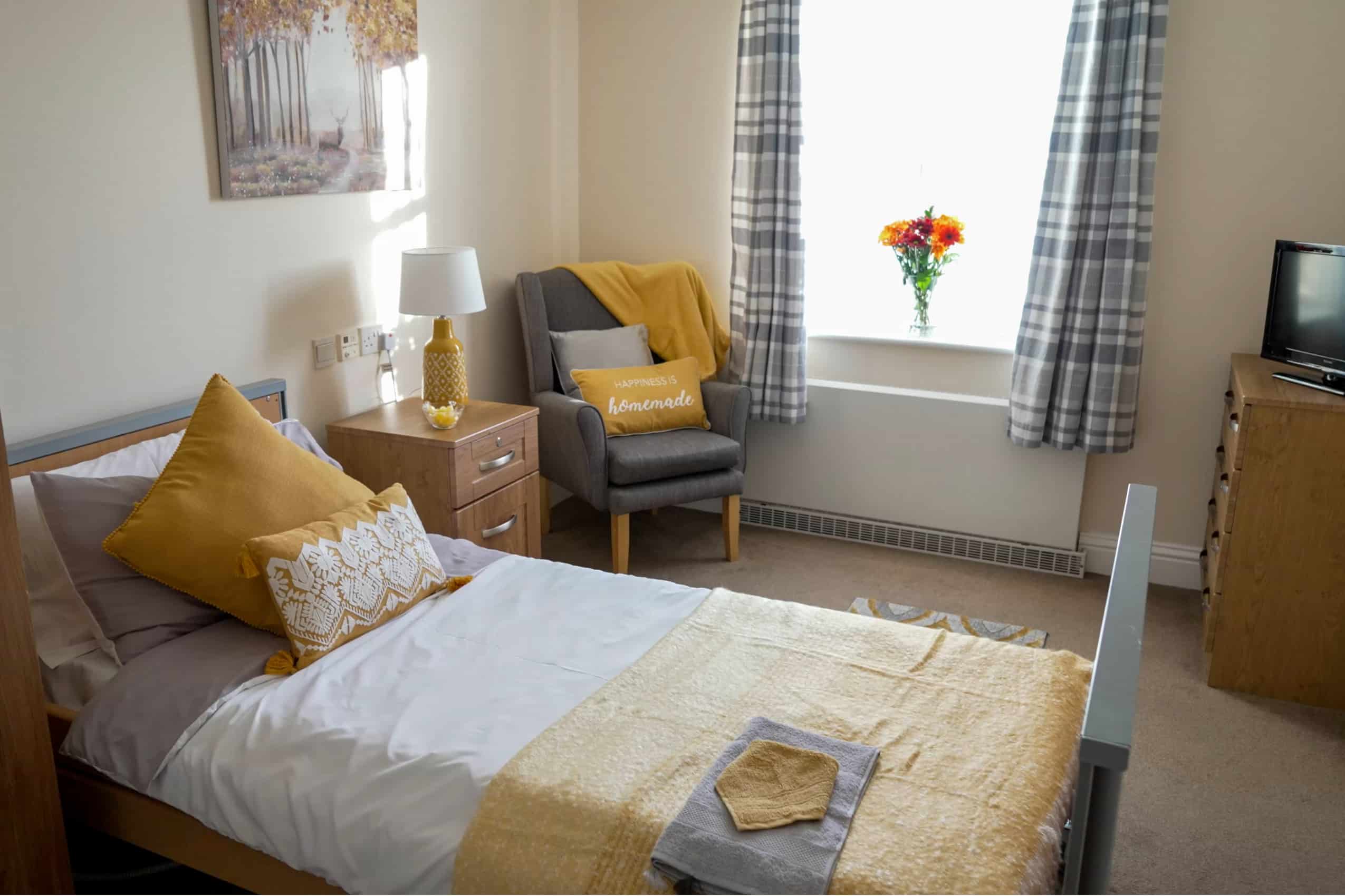 Newly refurbished bedroom with yellow and grey decor at Basildon care home Cameron House.