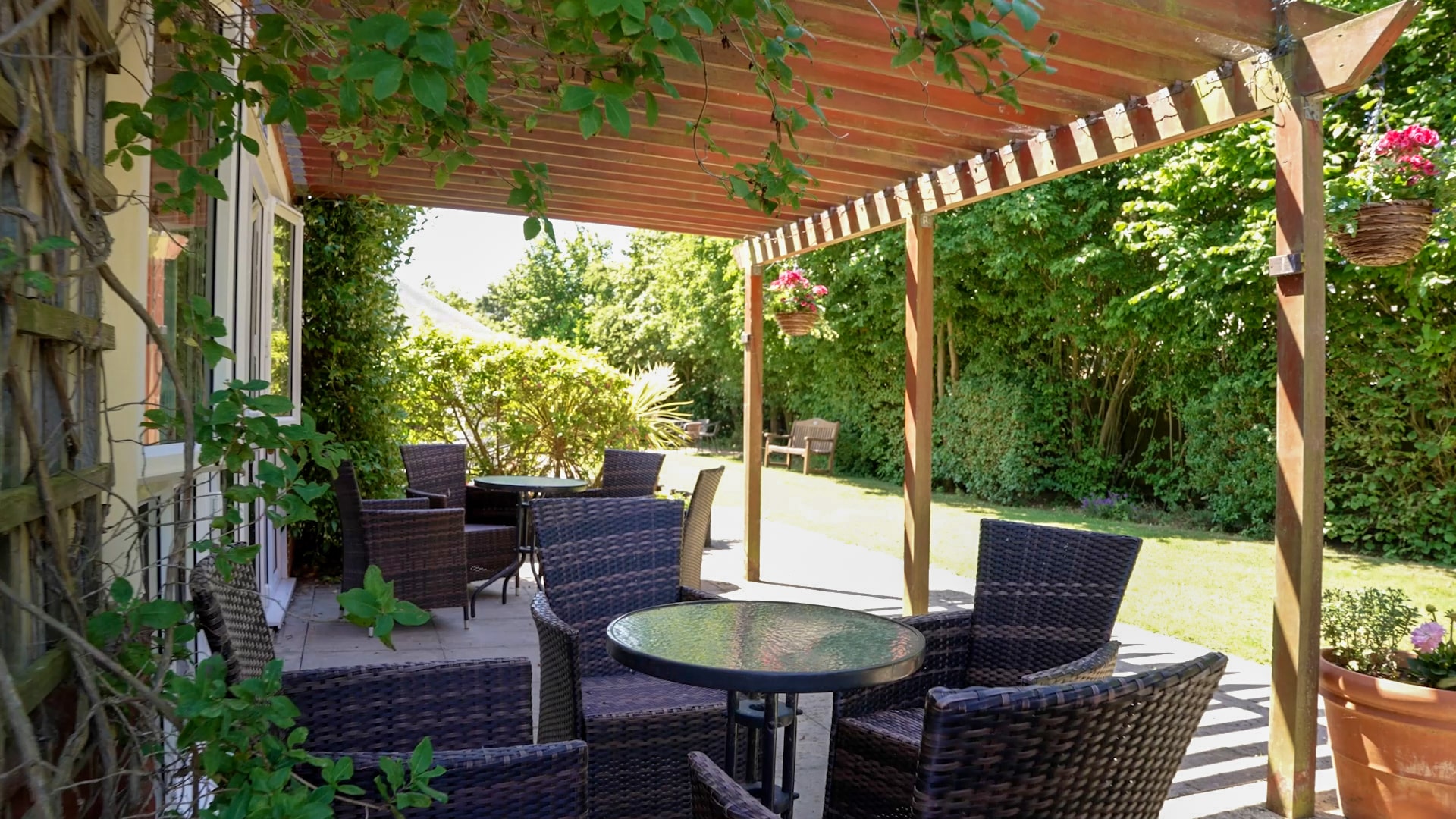 A shady seating area under the pergola and the garden at Lily House Care Home in Ely.