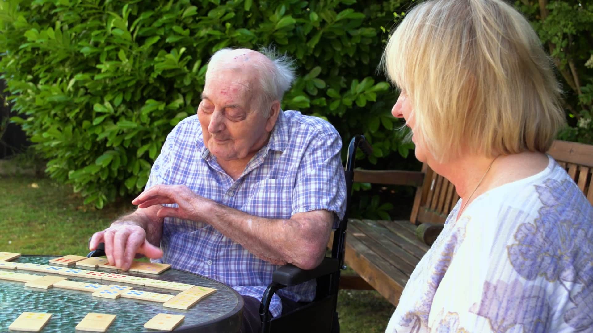 A resident and their relative playing dominoes in the garden at Lily House Care Home in Ely.
