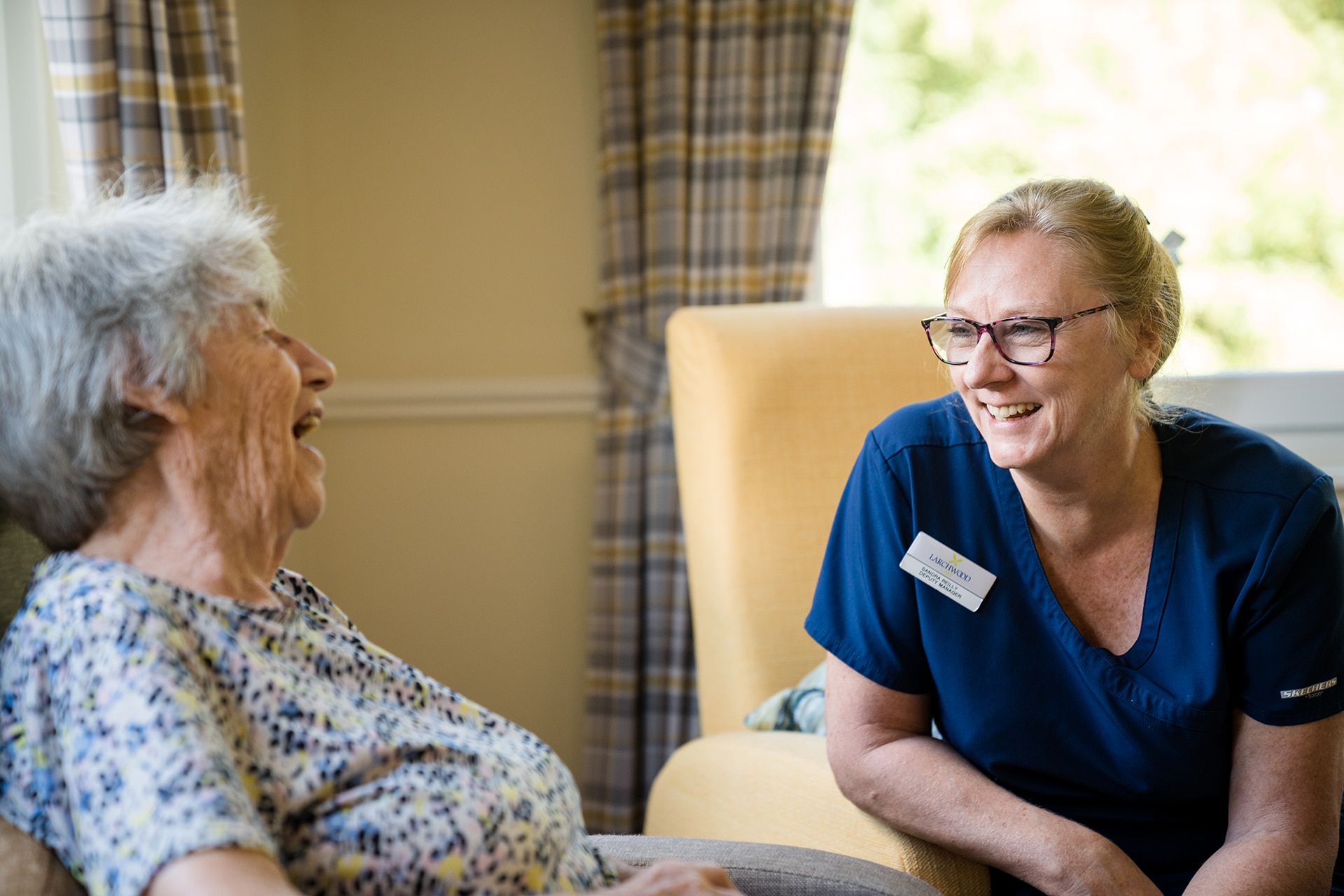 A resident chatting enjoying a chat with the manager of Muirton House in one of the home's many lounges.