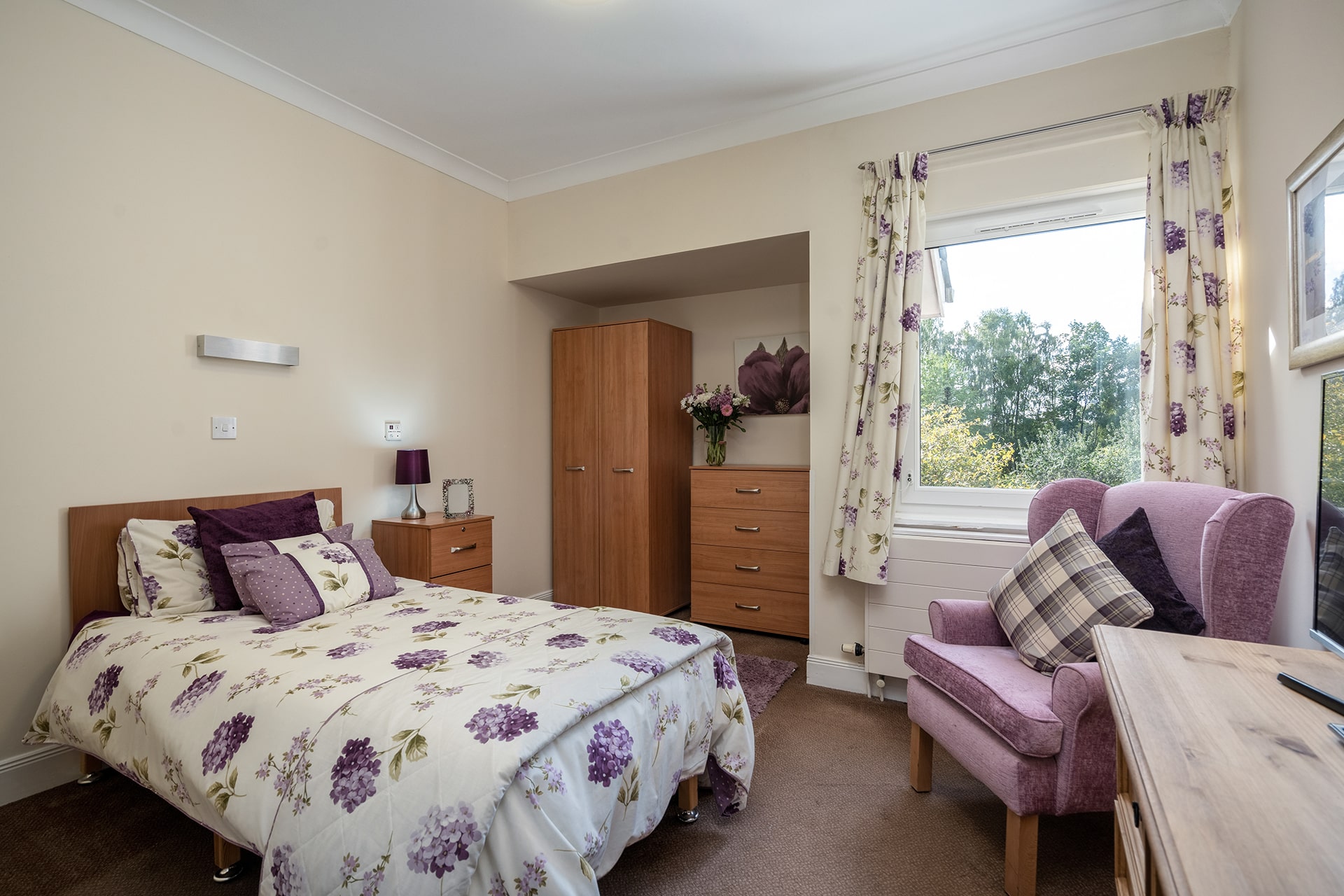 Tastefully decorated first floor bedroom at Muirton House Care Home with views of the garden.