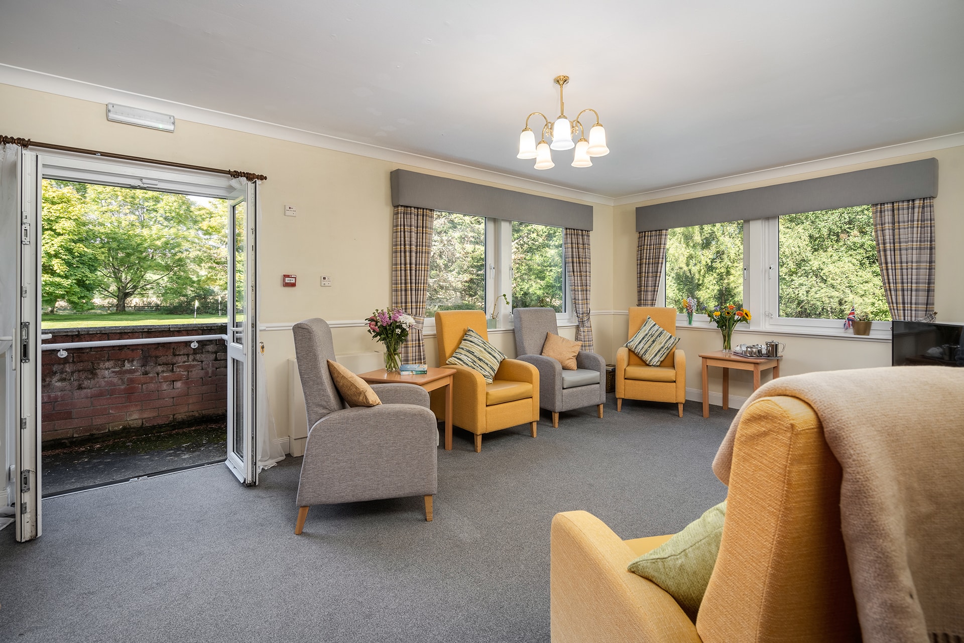 A bright and spacious ground floor lounge at Muirton House Care Home with views across the home's putting green.