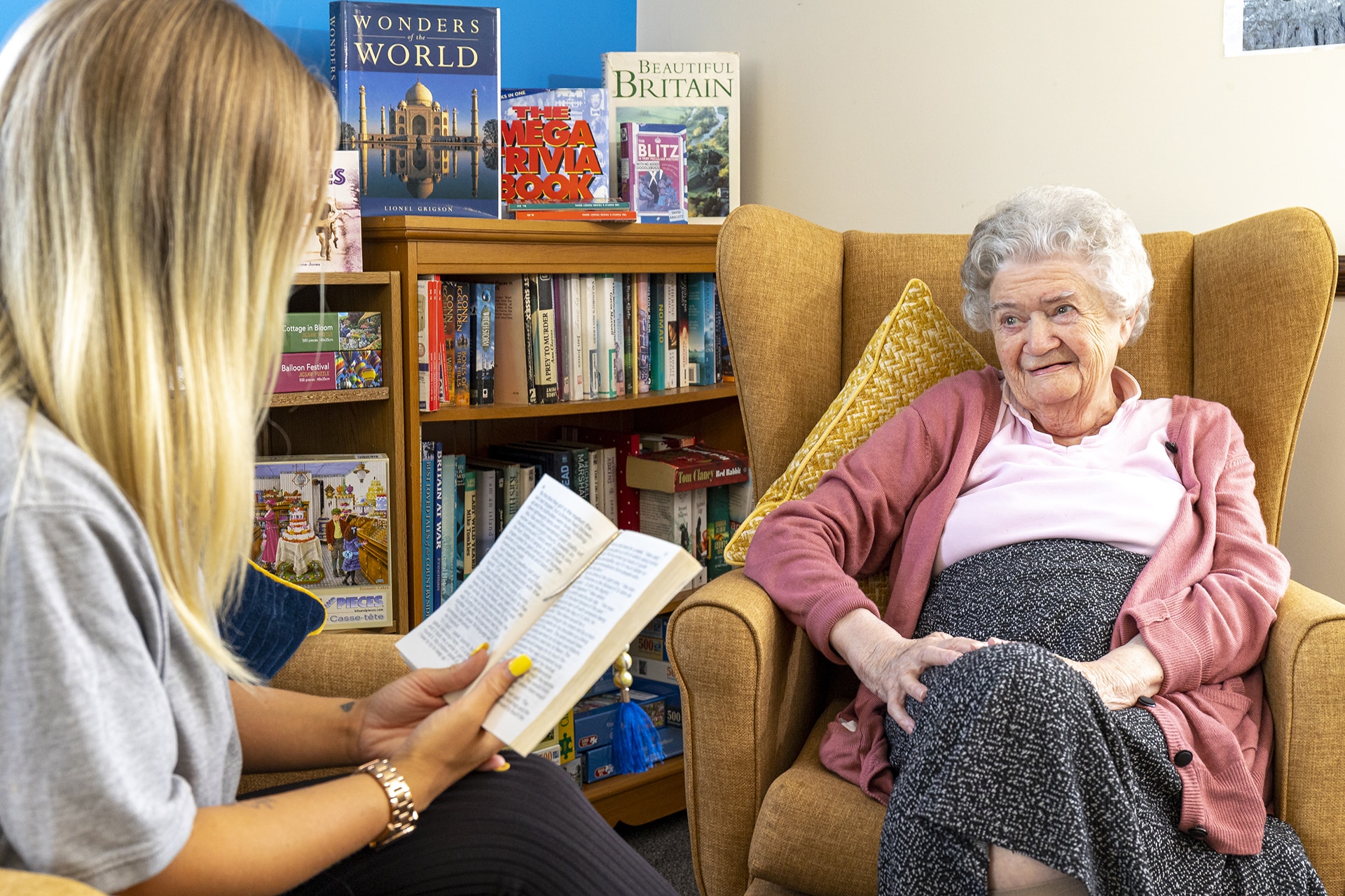 Resident and team member in the reading corner at Cavell House Care Home in Shoreham-by-Sea.