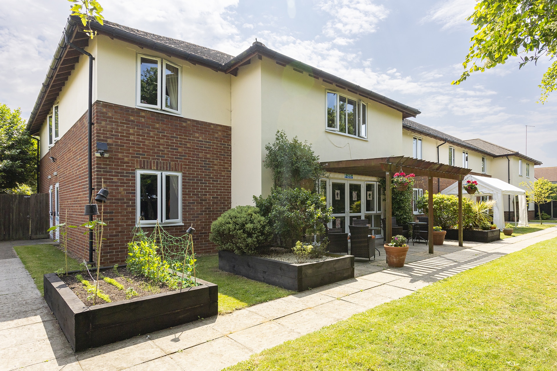 Rear view of Lily House Care Home in Ely with a view of the home's raised planters and garden terrace.