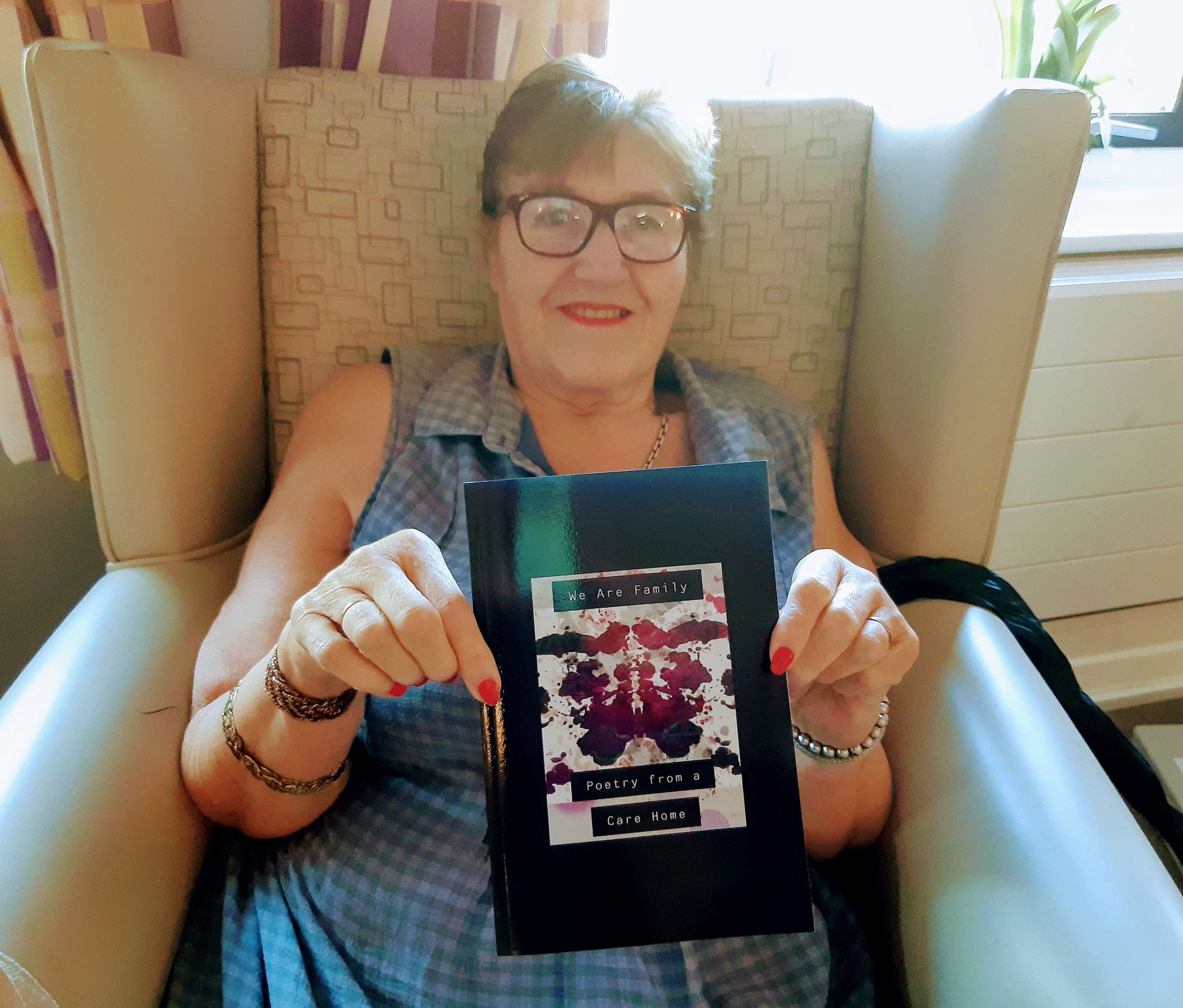 Taunton Care Home resident Margaret Hill with a copy of the Oake Meadows poetry book.