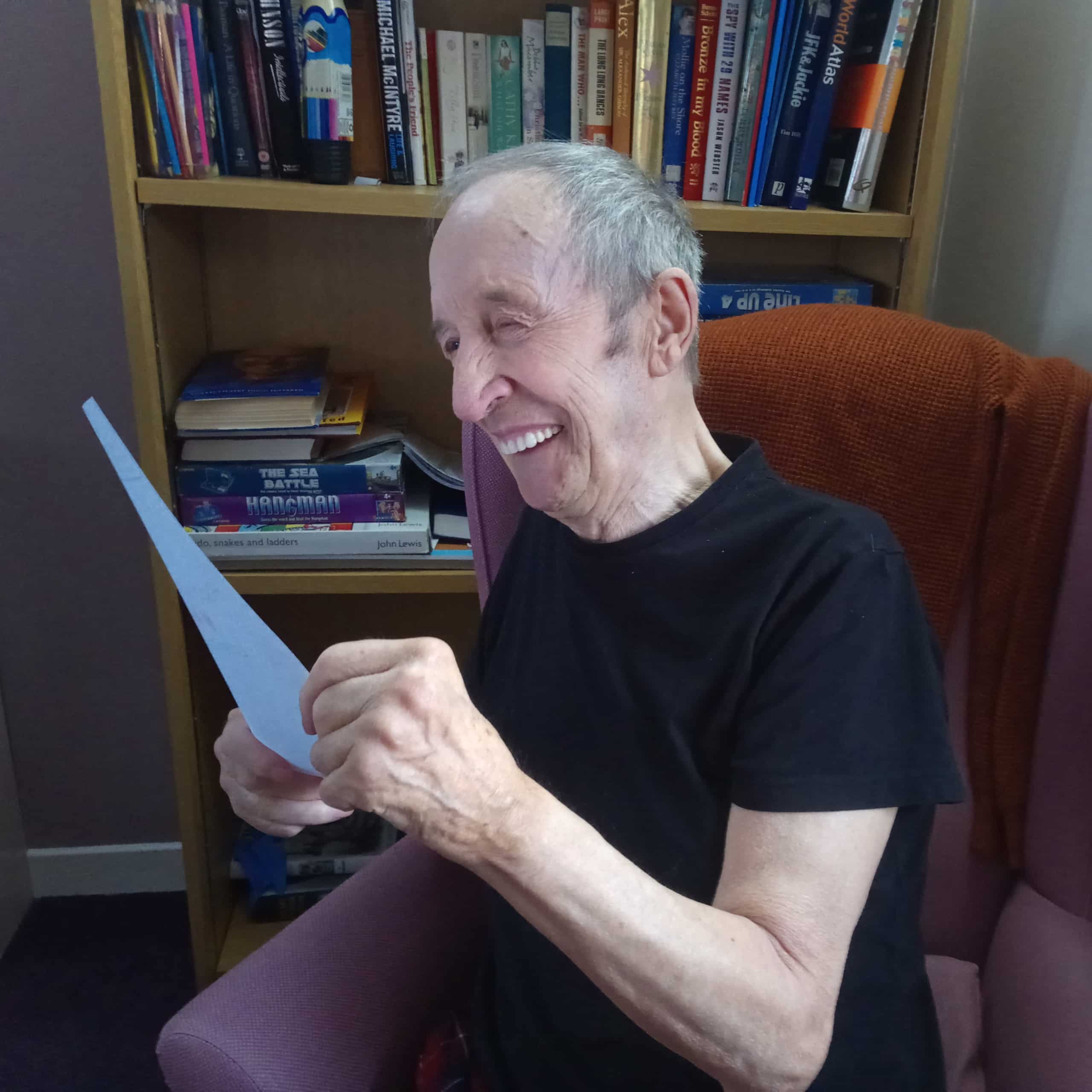 Stuart, a resident of Kingsgate Care Home in East Kilbride, smiling as he reads a Happygram from his wife.