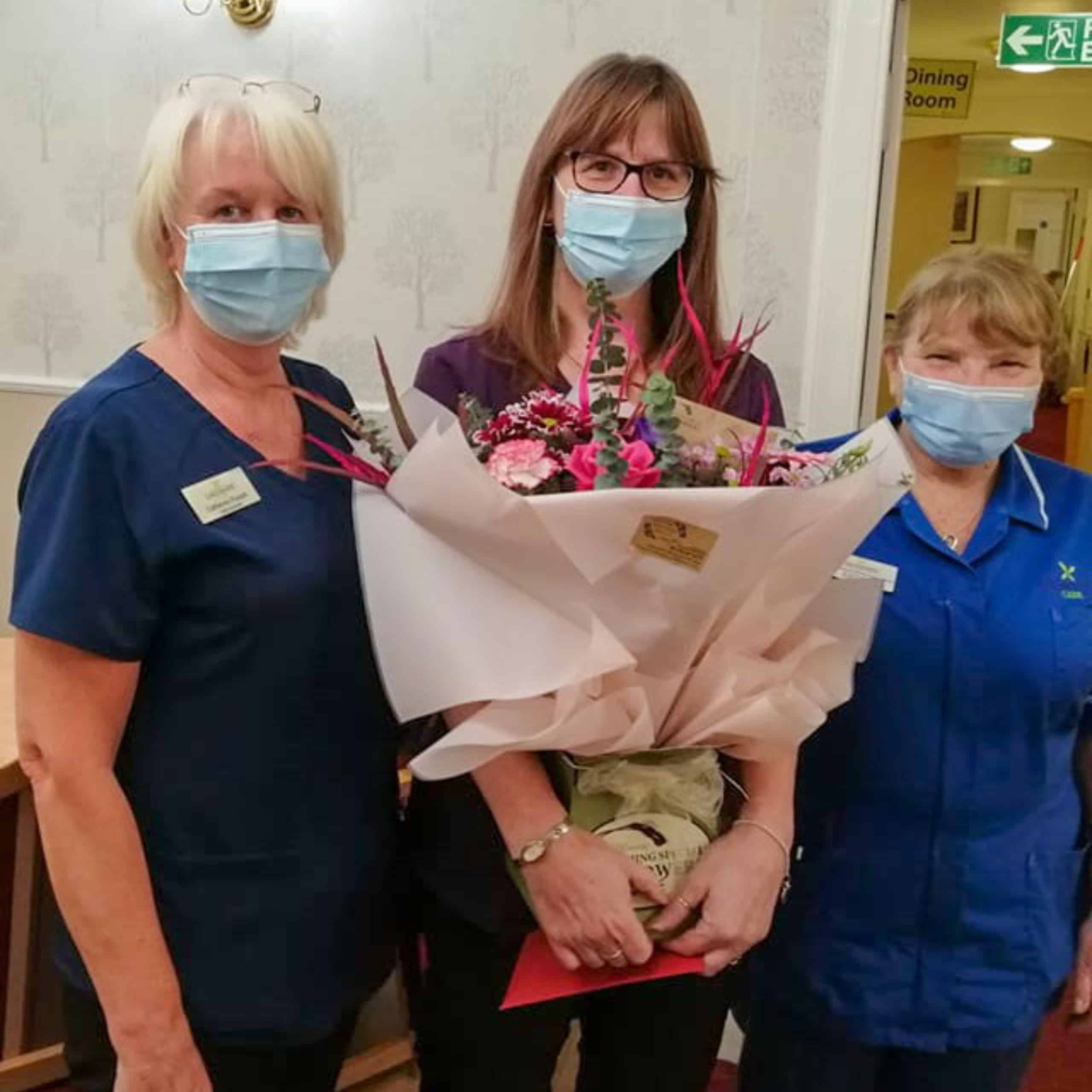 Muirton House Care Home's administrator Gill Rennie celebrates 20 years of continued service with a certificate and flowers from her colleagues.